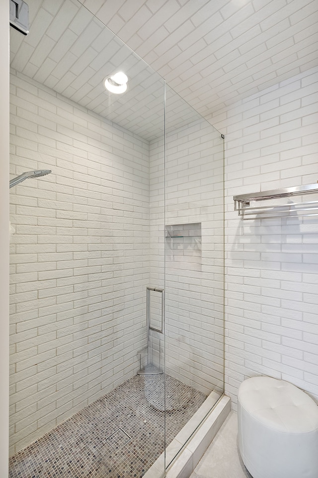 bathroom with a shower with shower door and tile walls