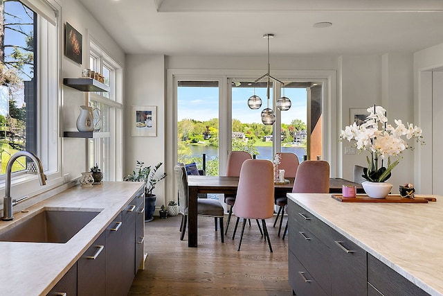 dining space featuring dark wood-style flooring, a chandelier, and a water view