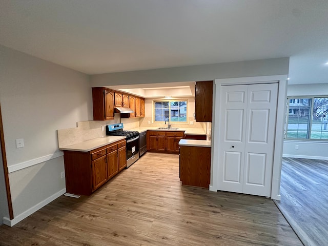 kitchen featuring light wood-type flooring, sink, dishwasher, and stainless steel range oven