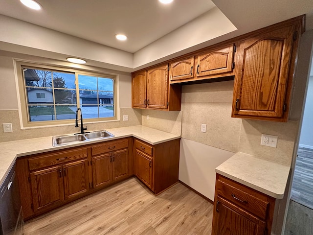 kitchen with stainless steel dishwasher, tasteful backsplash, sink, and light hardwood / wood-style flooring