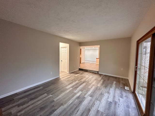 unfurnished room featuring wood-type flooring and a textured ceiling