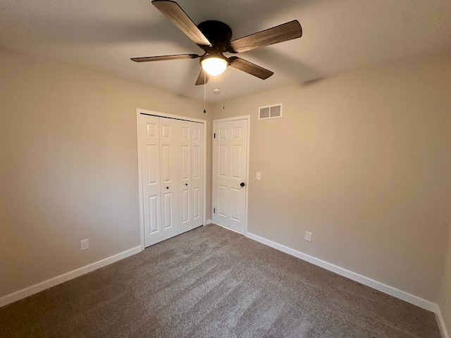 unfurnished bedroom featuring ceiling fan, dark carpet, and a closet