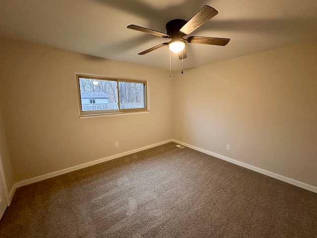 empty room with ceiling fan and dark carpet