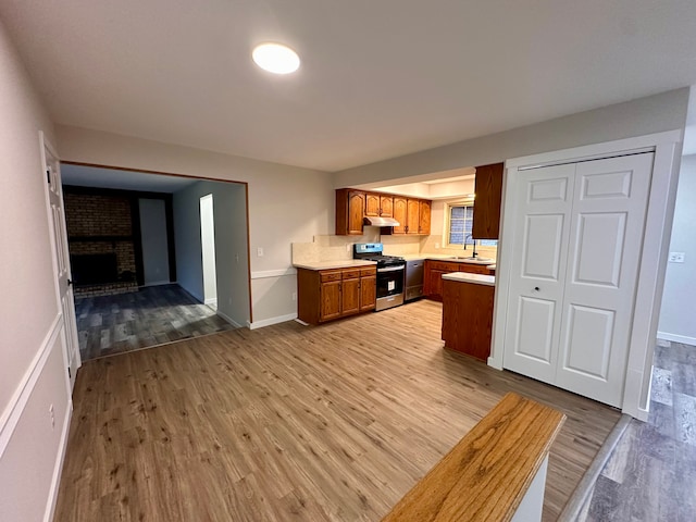 kitchen featuring light hardwood / wood-style floors, sink, a fireplace, and stainless steel stove