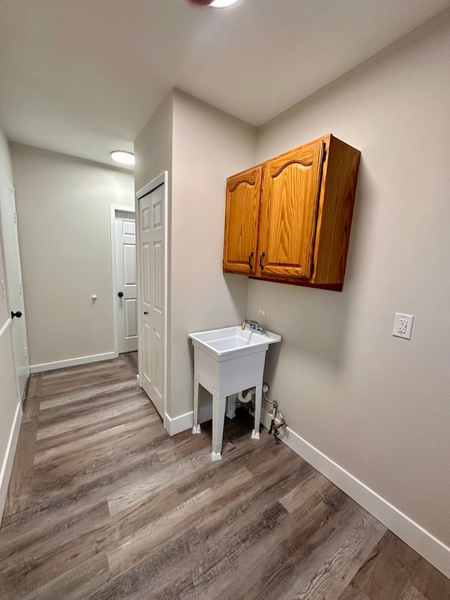 laundry area featuring hardwood / wood-style flooring, cabinets, and sink