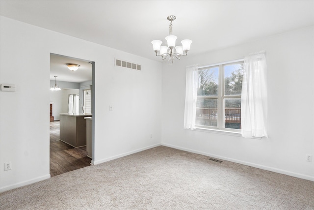 carpeted empty room featuring a notable chandelier