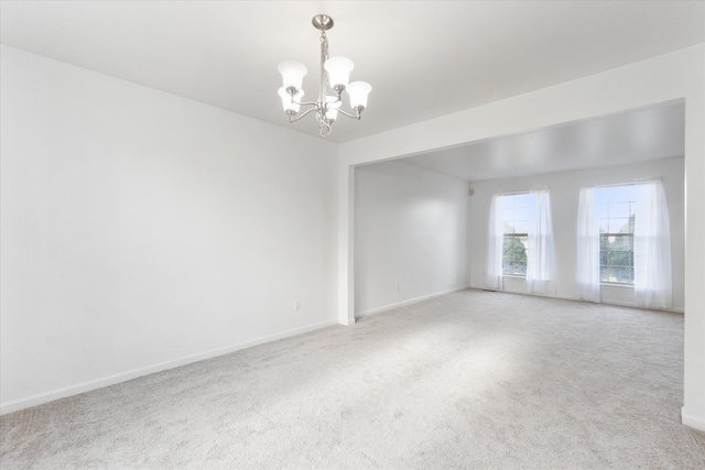 spare room with a chandelier and carpet