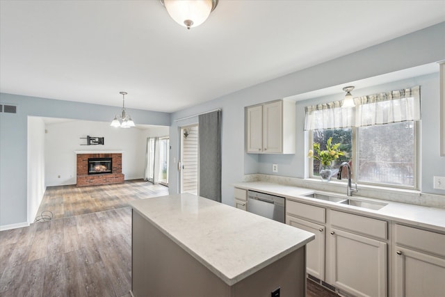 kitchen with a brick fireplace, sink, dishwasher, dark hardwood / wood-style floors, and a kitchen island