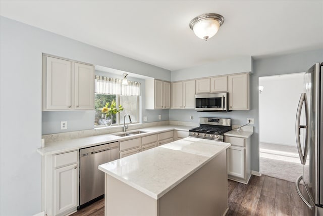 kitchen with light stone countertops, stainless steel appliances, sink, dark hardwood / wood-style floors, and a kitchen island