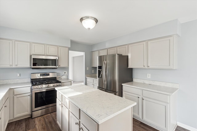 kitchen with white cabinets, dark hardwood / wood-style flooring, stainless steel appliances, and a kitchen island