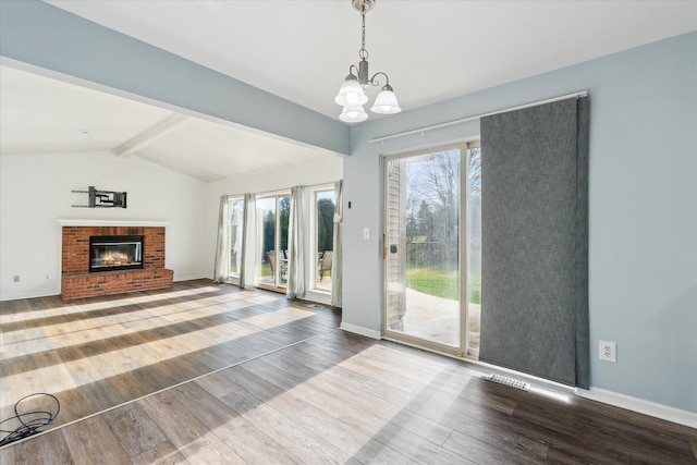 unfurnished living room featuring a fireplace, a chandelier, plenty of natural light, and hardwood / wood-style floors