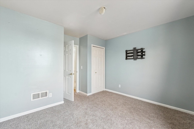 unfurnished bedroom featuring light carpet and a closet