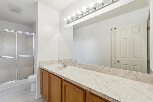 bathroom with tile patterned floors, vanity, toilet, and a shower with shower door