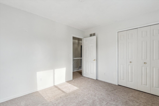 unfurnished bedroom with light colored carpet and a closet