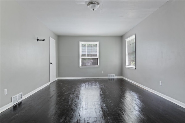 spare room featuring dark hardwood / wood-style flooring and plenty of natural light