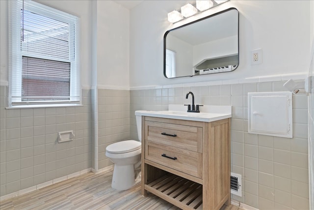 bathroom featuring vanity, toilet, and tile walls