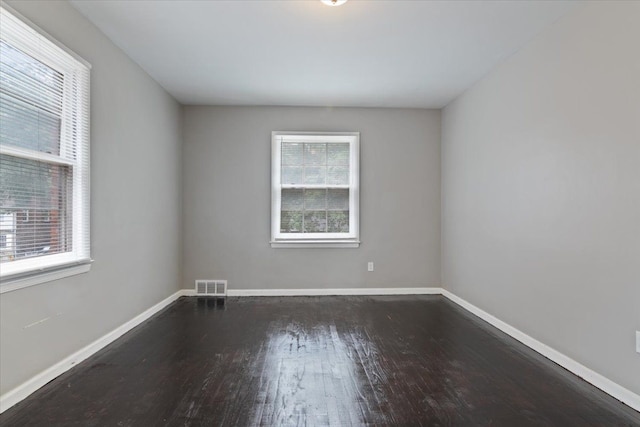 spare room with dark hardwood / wood-style flooring and a wealth of natural light