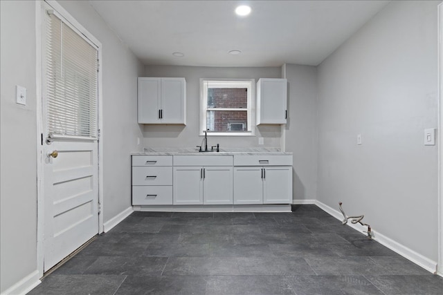 kitchen featuring light stone countertops, sink, and white cabinets