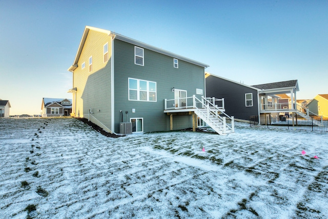 snow covered property with central AC unit and a wooden deck