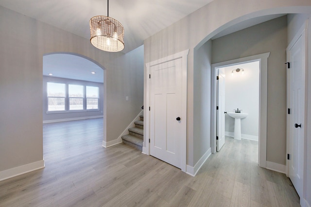 hall with light hardwood / wood-style flooring, a chandelier, and sink