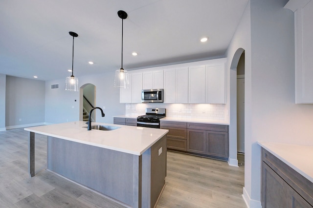 kitchen featuring white cabinetry, sink, decorative light fixtures, and appliances with stainless steel finishes