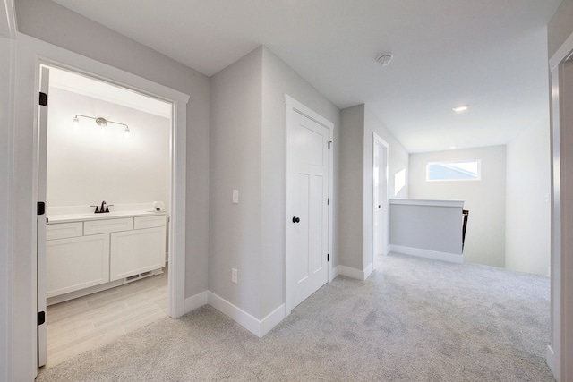 hall featuring light colored carpet and sink