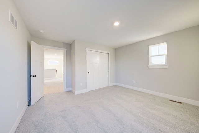 unfurnished bedroom featuring light colored carpet and a closet