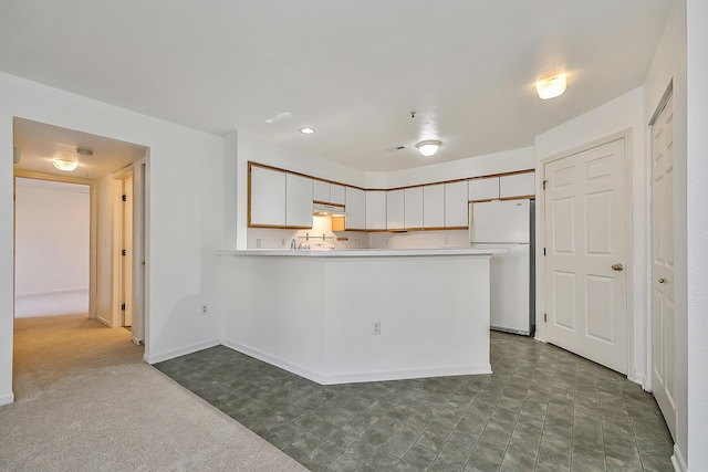 kitchen featuring white fridge, white cabinetry, kitchen peninsula, and dark carpet