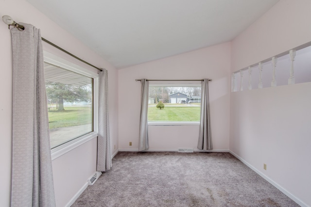 unfurnished room with light colored carpet, a wealth of natural light, and lofted ceiling