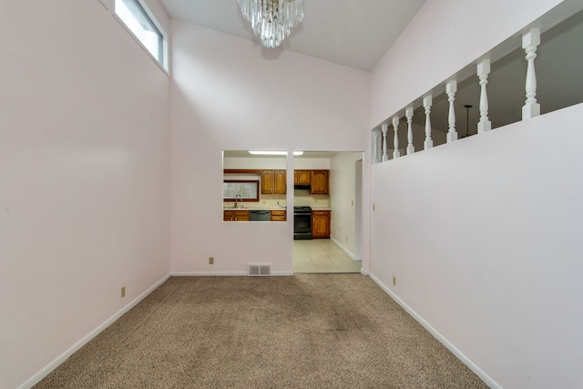 unfurnished living room with light carpet, a high ceiling, a chandelier, and sink