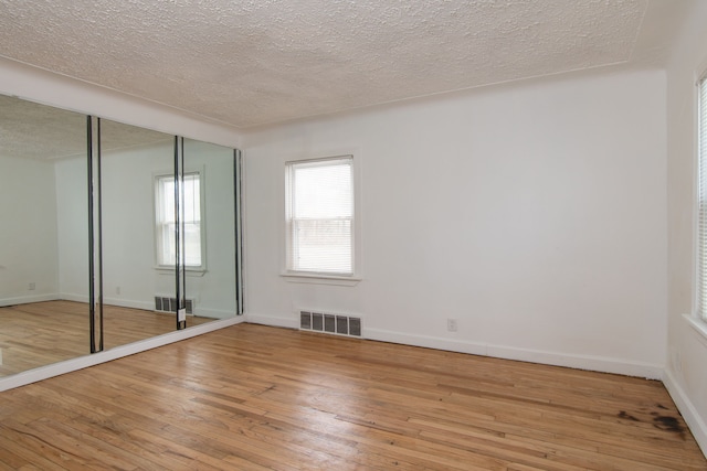 spare room featuring light wood-type flooring and a textured ceiling