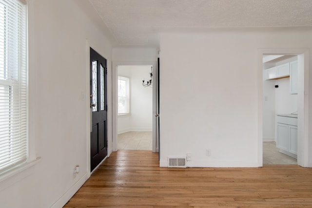 corridor with light hardwood / wood-style floors and a textured ceiling