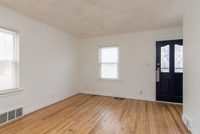 foyer featuring light wood-type flooring and a textured ceiling