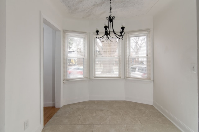 unfurnished dining area featuring light tile patterned flooring, a textured ceiling, and a notable chandelier