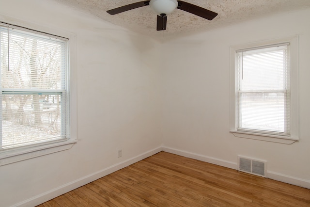 empty room with ceiling fan, hardwood / wood-style floors, and a textured ceiling