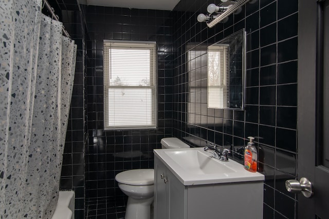 full bathroom featuring tile walls, toilet, vanity, and shower / bath combo