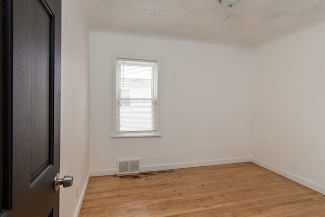 empty room featuring a textured ceiling and light wood-type flooring