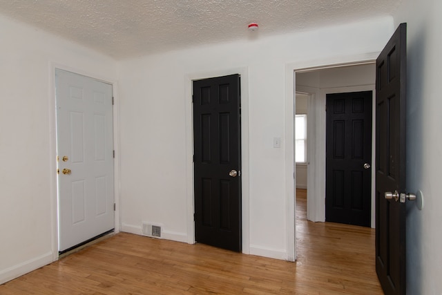 unfurnished room with light hardwood / wood-style floors and a textured ceiling