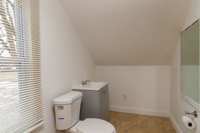 bathroom featuring toilet, vanity, and lofted ceiling