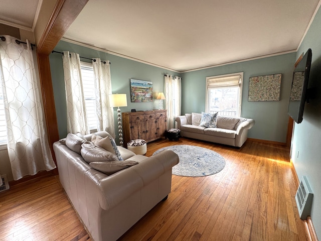 living room featuring light wood-type flooring, ornamental molding, and a wealth of natural light