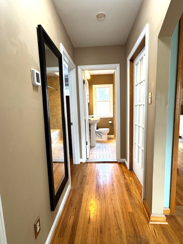 corridor with light wood-type flooring and sink