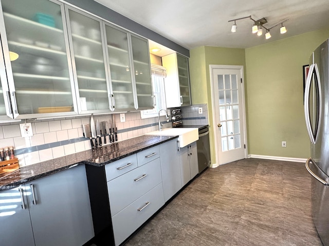 kitchen with french doors, sink, dark stone countertops, appliances with stainless steel finishes, and tasteful backsplash