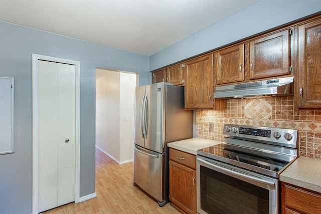 kitchen with decorative backsplash, stainless steel appliances, and light hardwood / wood-style flooring