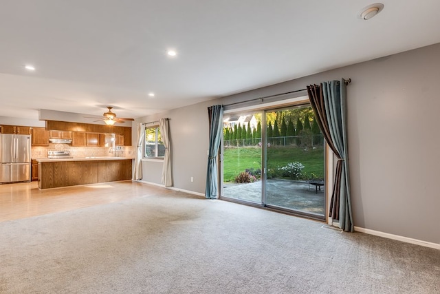 unfurnished living room featuring light carpet and ceiling fan