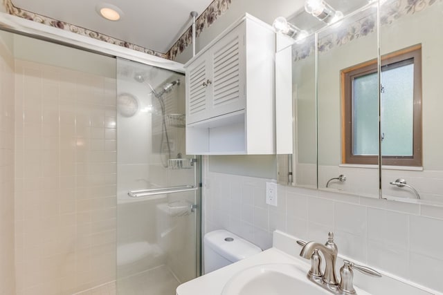 bathroom featuring sink, toilet, a shower with door, and tile walls