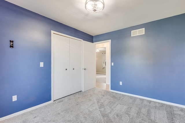 unfurnished bedroom with a closet and light colored carpet