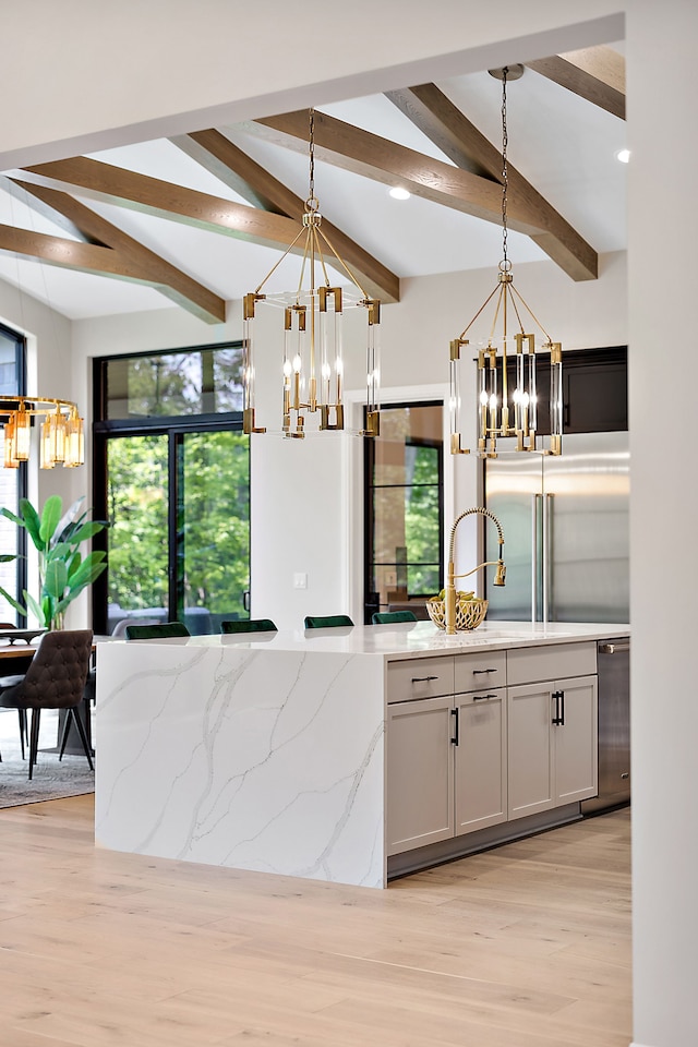 kitchen featuring light stone counters, light hardwood / wood-style floors, hanging light fixtures, and appliances with stainless steel finishes