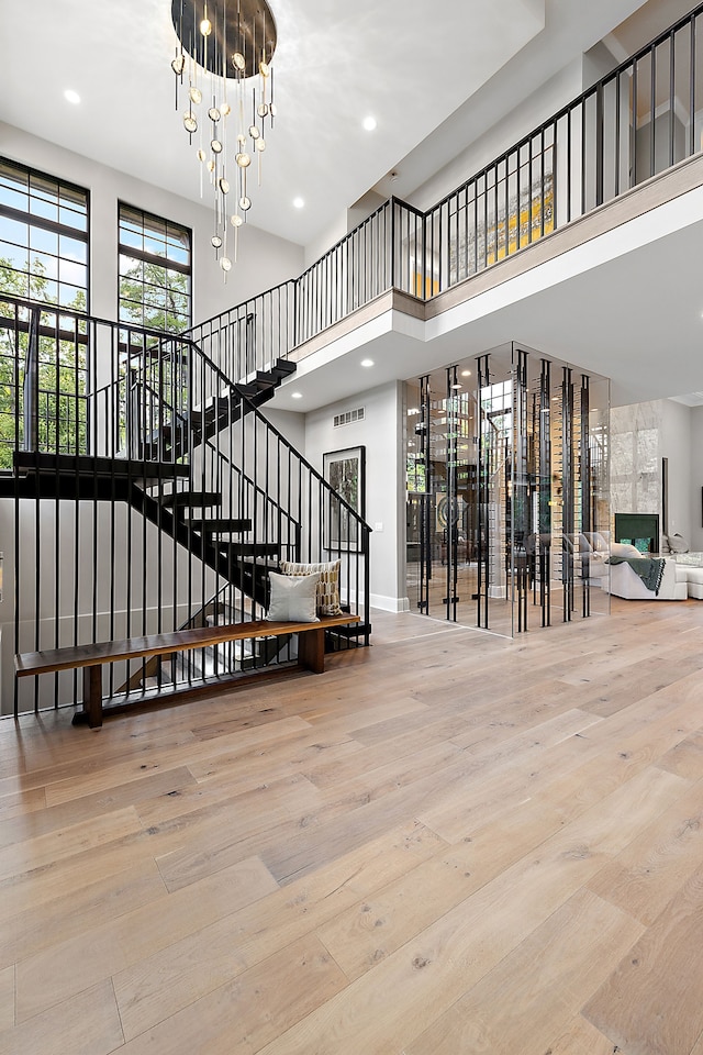 stairway with wood-type flooring, a high ceiling, and a chandelier