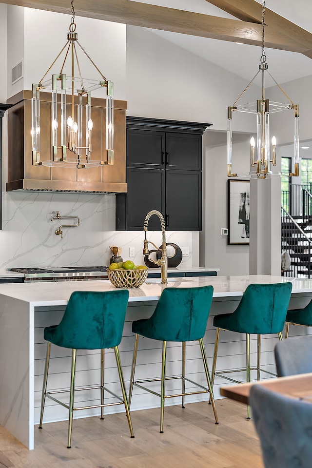 kitchen with backsplash, hanging light fixtures, vaulted ceiling, light hardwood / wood-style flooring, and a breakfast bar area