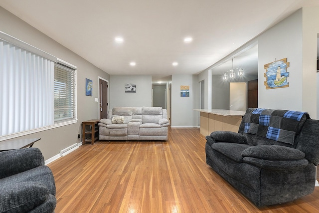 living room featuring hardwood / wood-style flooring, an inviting chandelier, and a baseboard heating unit